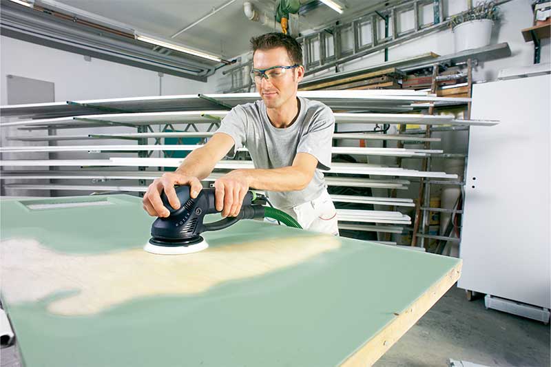 Una persona leviga una superficie verniciata di verde