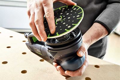 Un artigiano posiziona un platorello su una levigatrice Festool