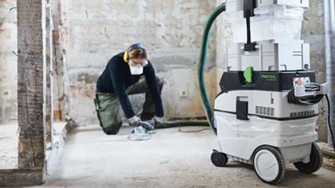 Un artigiano leviga un pavimento utilizzando il sistema di levigatura per pavimenti Festool con aspirazione.